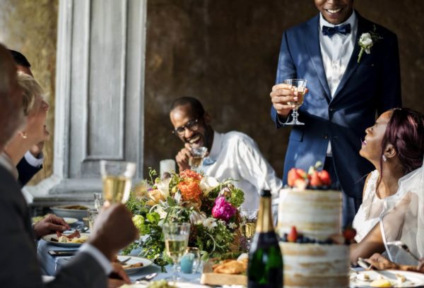 Wedding party laughing as a man gives his speech.