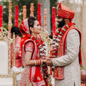 Indian bride and groom holding hands in wedding clothes.
