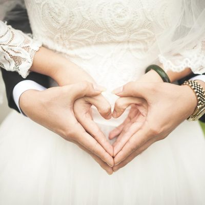 Bride and a groom making heart with their hands.